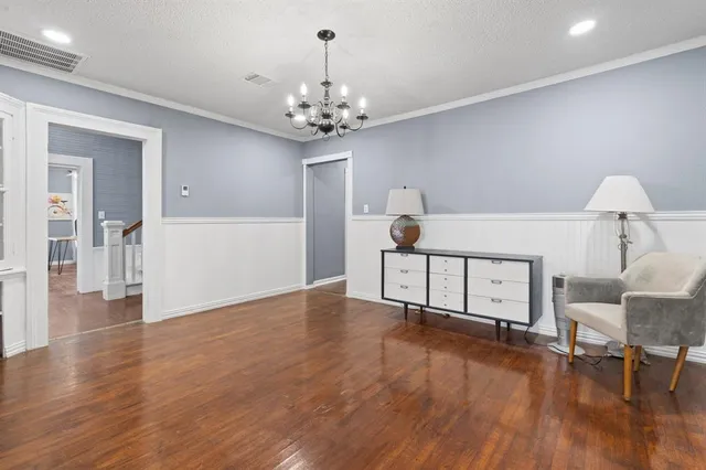 a view of a livingroom with wooden floor and a chandelier