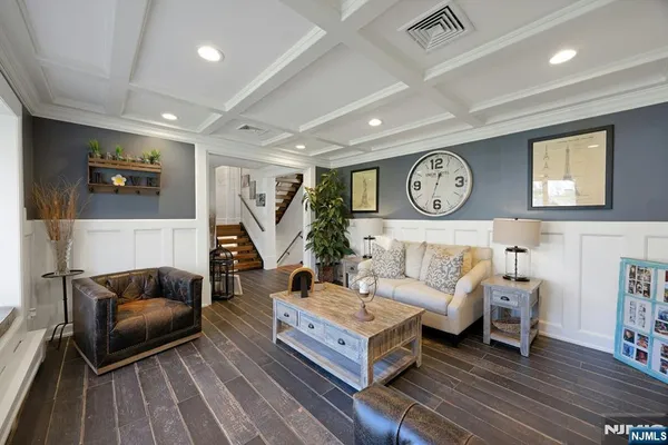 a kitchen with stainless steel appliances kitchen island granite countertop a stove a sink a refrigerator and white cabinets with wooden floor