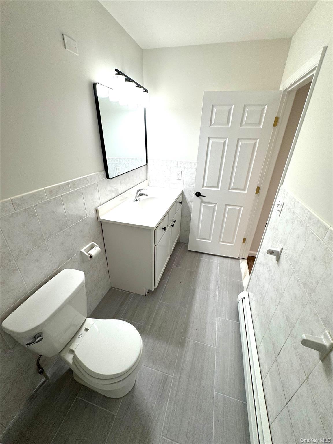 315 Main Street, Unit 3 Poughkeepsie, NY 12601 - Photo 8 of 13 a bathroom with a sink mirror vanity and toilet