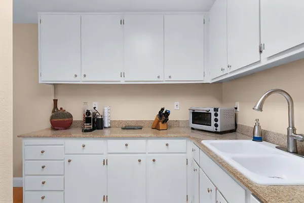 a kitchen with white cabinets and sink