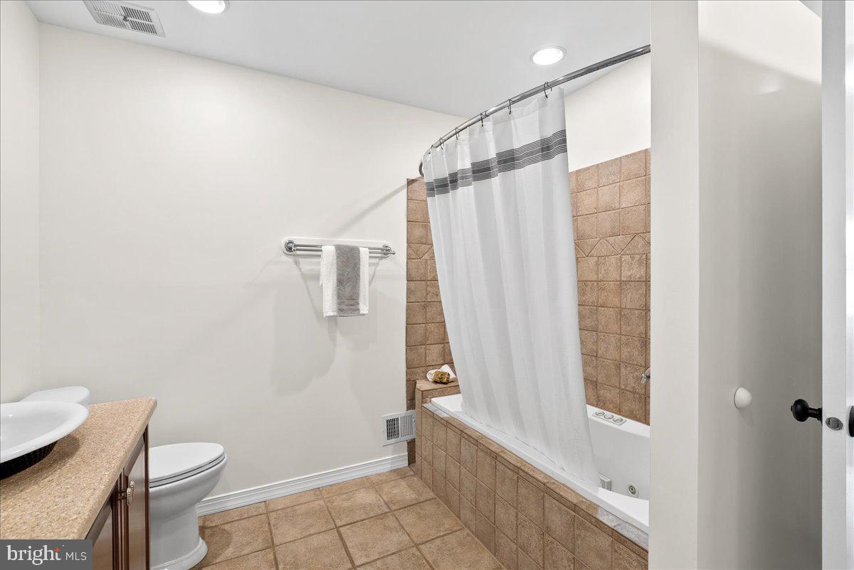 7596 Ruxton Drive Springfield, VA 22153 - Photo 23 of 40 a bathroom with a granite countertop bathtub a toilet and a shower