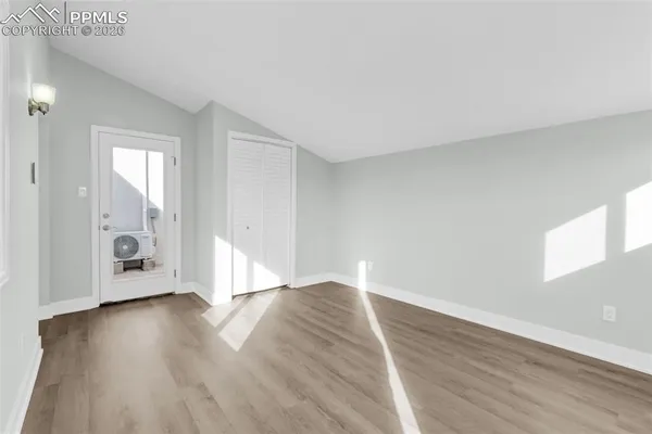 an empty room with wooden floor and windows
