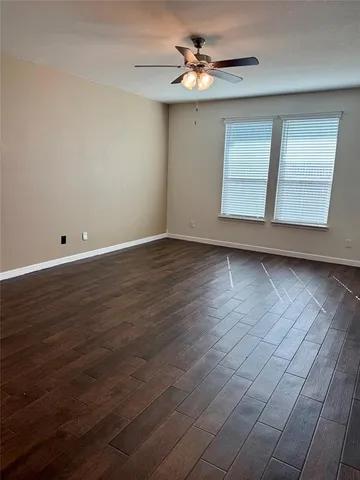 an empty room with wooden floor chandelier and windows