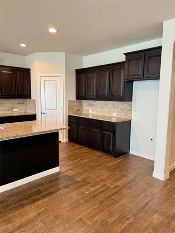 a view of kitchen with stainless steel appliances kitchen island wooden cabinets and granite counter top