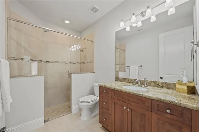 a bathroom with a granite countertop sink a toilet and shower