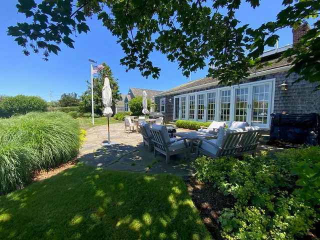 a view of a patio with table and chairs potted plants and large tree