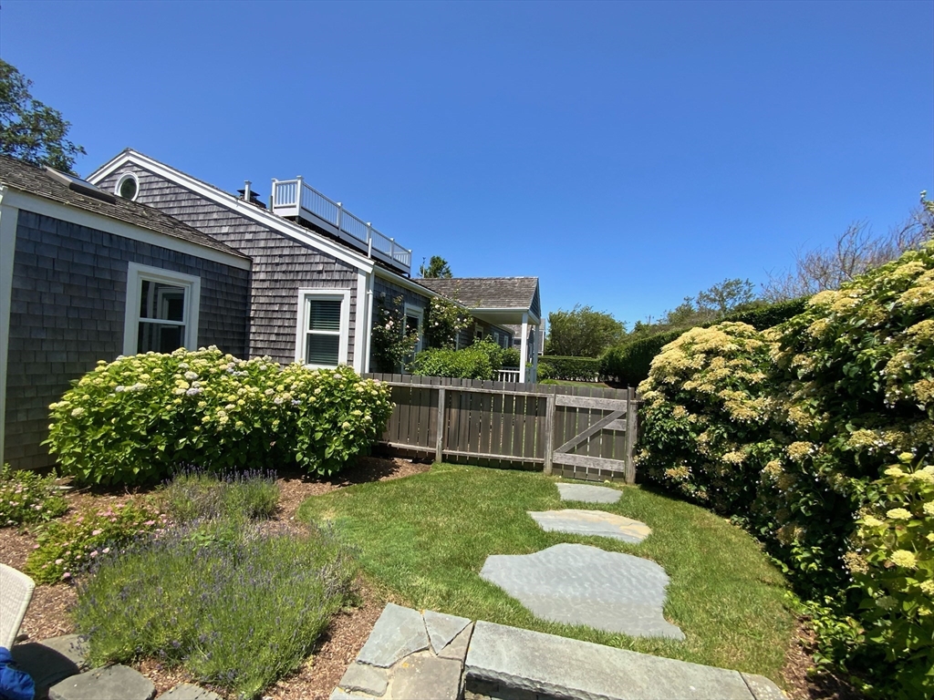 17 Burnell Street Nantucket, MA 02554 - Photo 6 of 24 a backyard of a house with a garden and plants