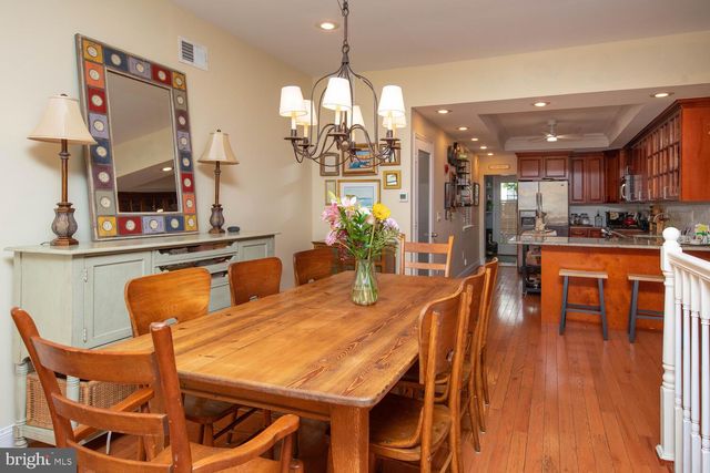 a dining room with wooden floor a chandelier a glass table and chairs