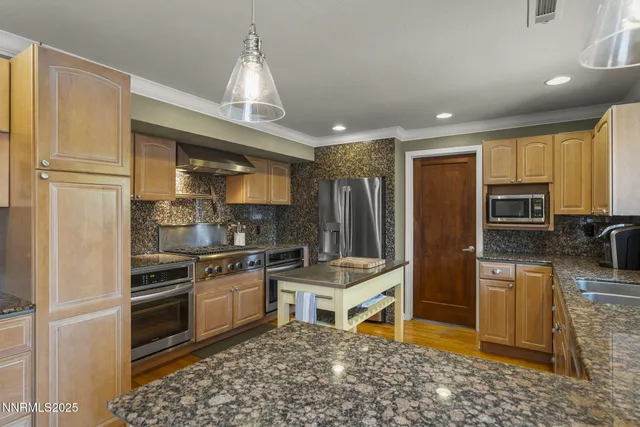 a kitchen with stainless steel appliances granite countertop a refrigerator a stove and a sink