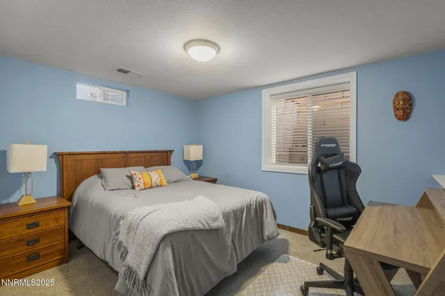 a bedroom with a bed a desk and chair with wooden floor