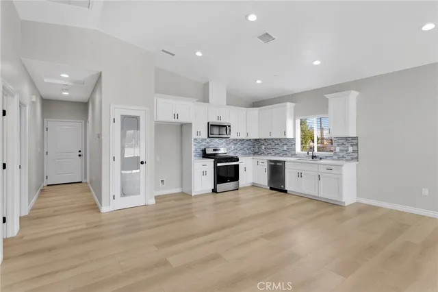 a large kitchen with stainless steel appliances cabinets a sink and a wooden floor