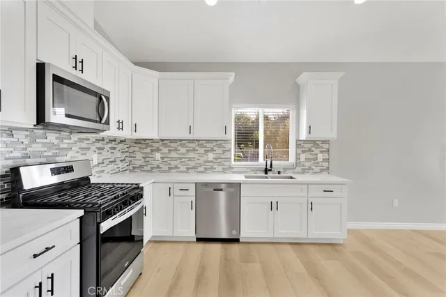 a kitchen with stainless steel appliances granite countertop a stove a sink and a microwave