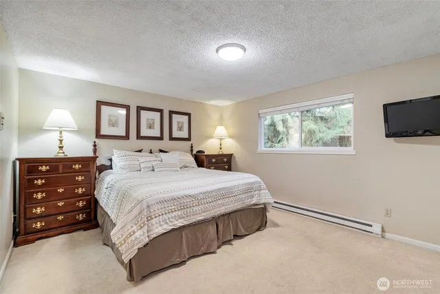 a bedroom with a bed a mirror on dresser and a window