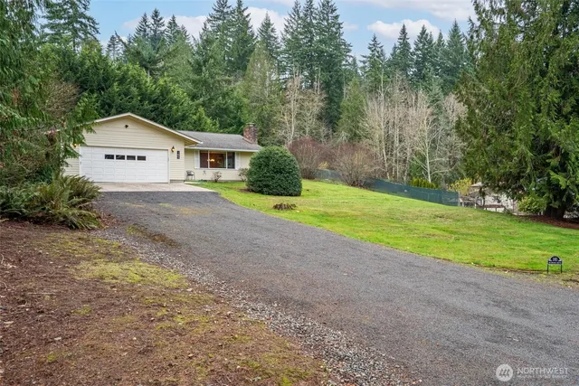 a view of a house with a yard and large trees