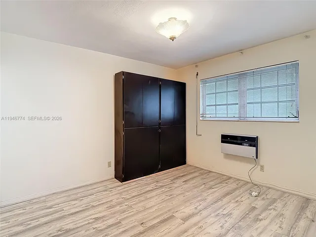 an empty room with wooden floor cabinet and windows