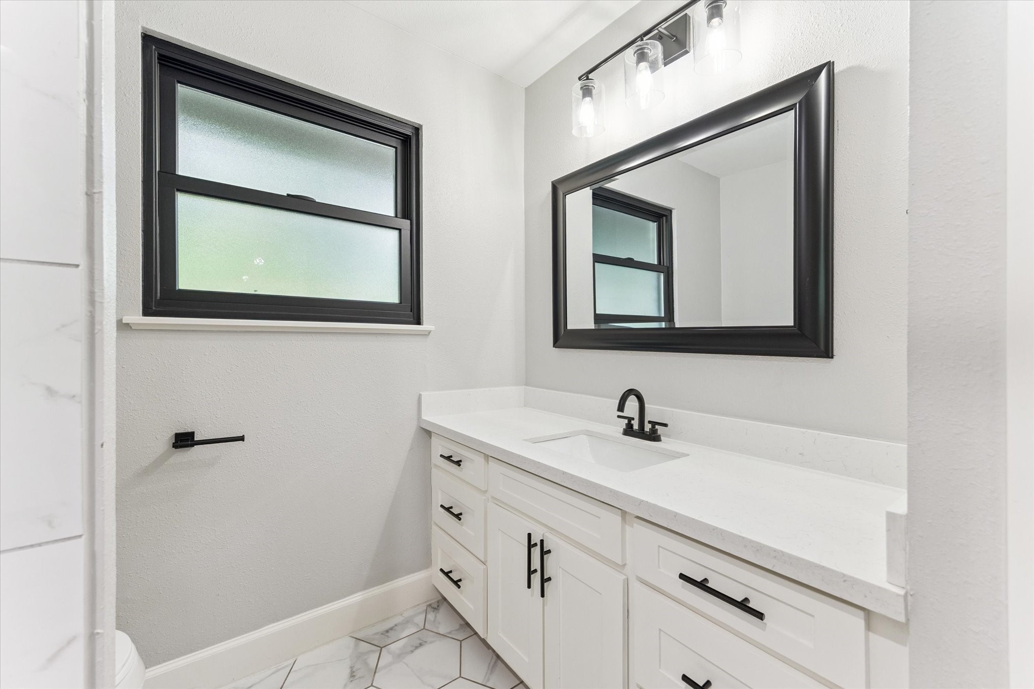 5414 Sanford Road Houston, TX 77096 - Photo 26 of 32 White cabinetry is juxtaposed with matte black hardware in this windowed secondary bathroom.