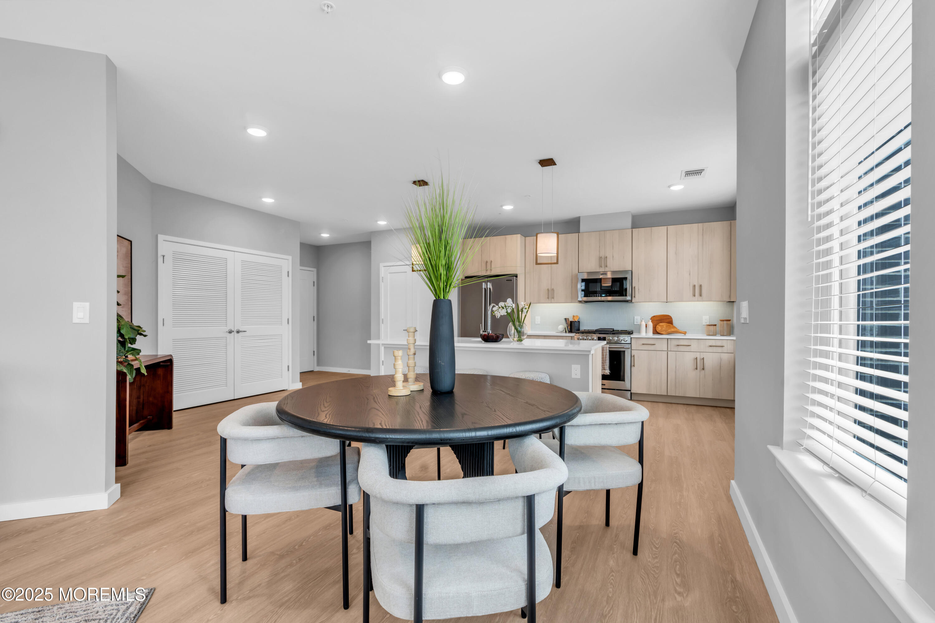 120 Monmouth Street, Unit 308 Red Bank, NJ 07701 - Photo 12 of 37 a kitchen with stainless steel appliances kitchen island granite countertop a dining table chairs and a refrigerator