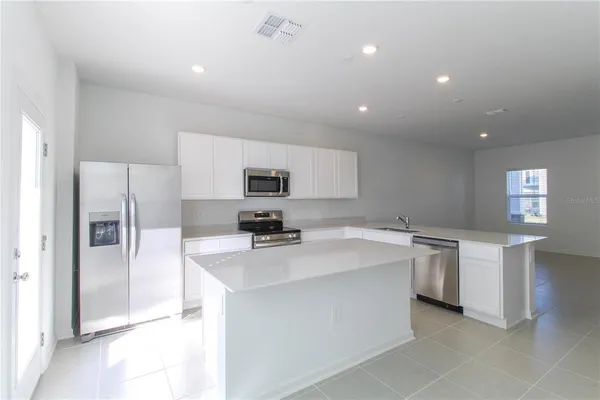 a kitchen that has a lot of white cabinets and stainless steel appliances