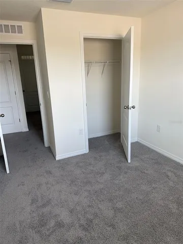 a bed sitting in a bedroom and dressers next to a window