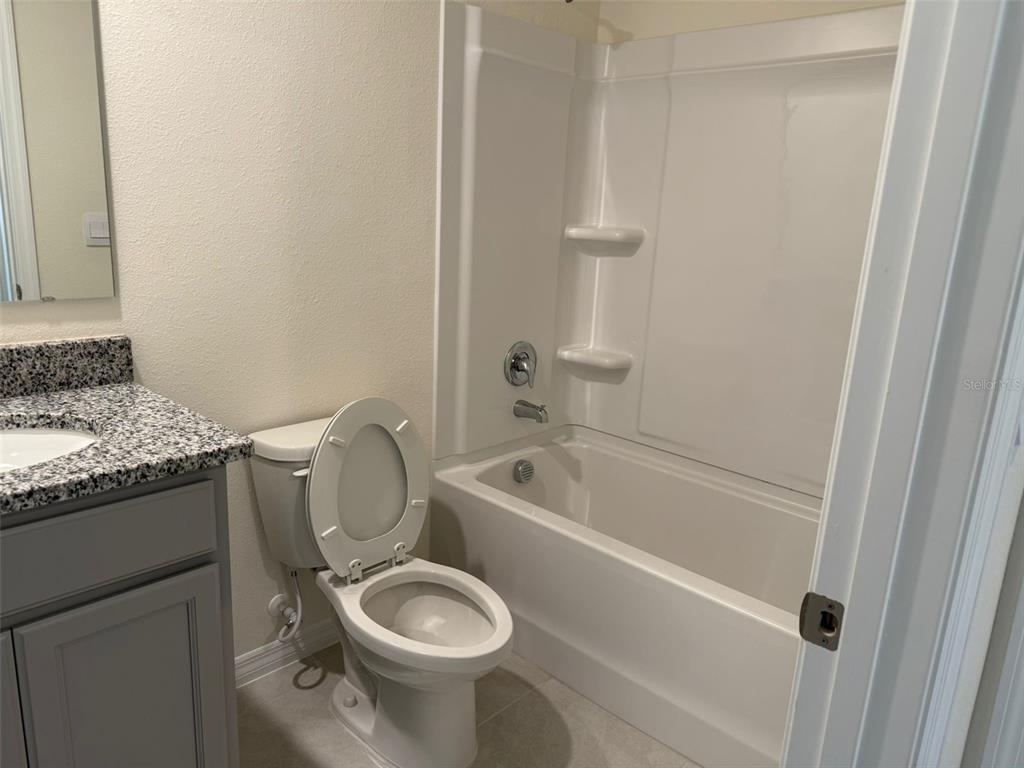 2914 Hudson Hammock Way St. Cloud, FL 34773 - Photo 26 of 30 a bathroom with a granite countertop sink toilet and bathtub