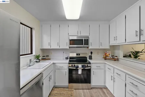 a kitchen with granite countertop a sink a stove and cabinets
