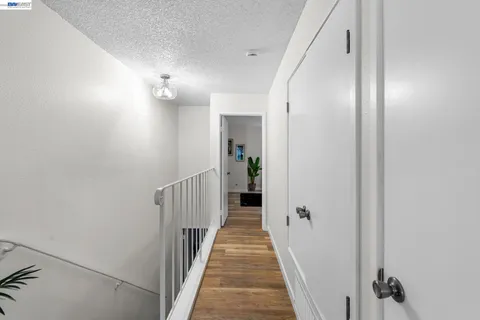 a view of a hallway with wooden floor and a bathroom