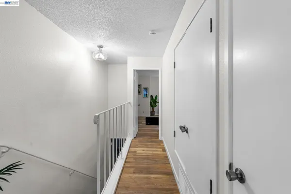 a view of a hallway with wooden floor and a bathroom