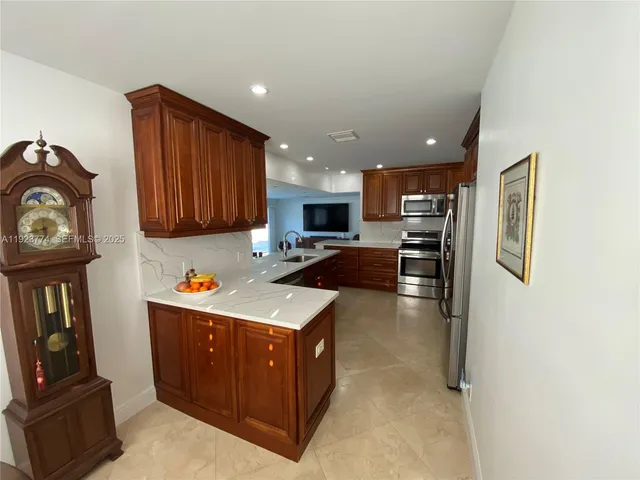 a kitchen with stainless steel appliances granite countertop a stove top oven a sink a refrigerator and cabinets