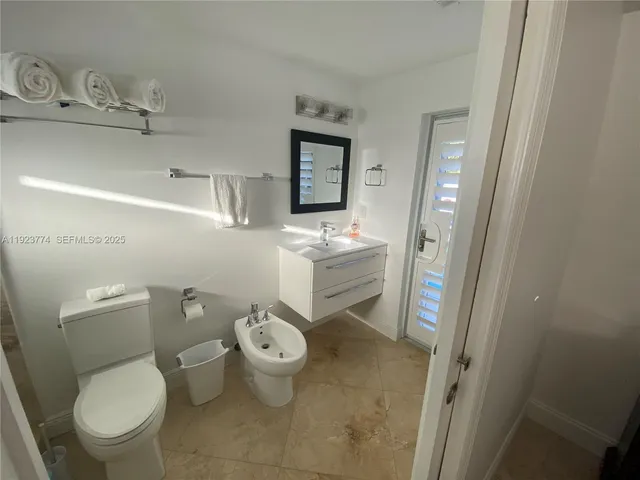 a bathroom with a granite countertop toilet and a sink