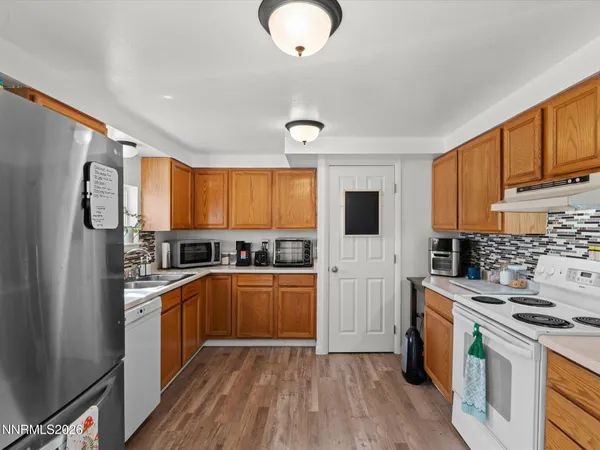 a kitchen with stainless steel appliances granite countertop a stove top oven a refrigerator a sink and dishwasher with wooden floor