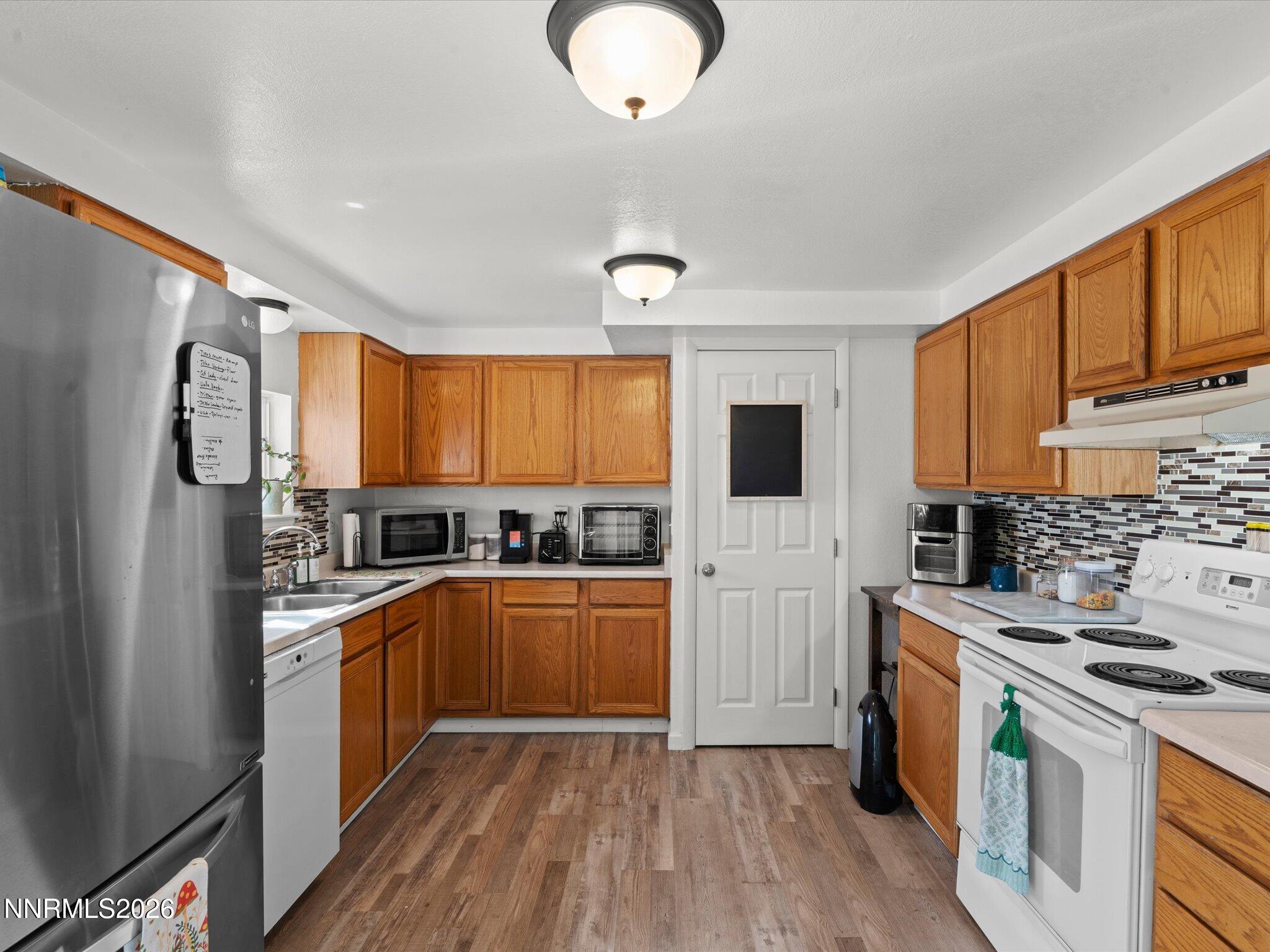 3320 Della Circle Fallon, NV 89406 - Photo 12 of 31 a kitchen with stainless steel appliances granite countertop a stove top oven a refrigerator a sink and dishwasher with wooden floor