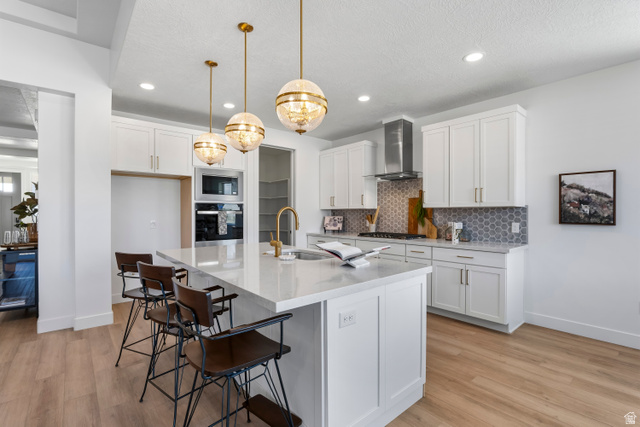624 North Legend Circle, Unit 480 Mapleton, UT 84664 - Photo 16 of 34 Kitchen with a kitchen breakfast bar, light wood finished floors, white cabinetry, light stone counters, and a center island with sink