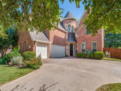 a front view of a house with a garden and trees