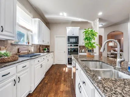 a kitchen with granite countertop a sink stove and cabinets