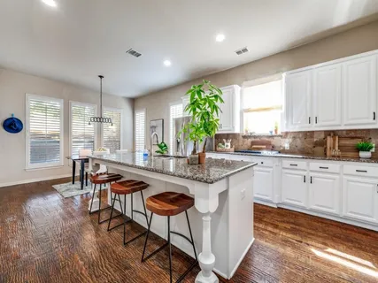 a kitchen with stainless steel appliances granite countertop wooden floor sink stove dining table and chairs