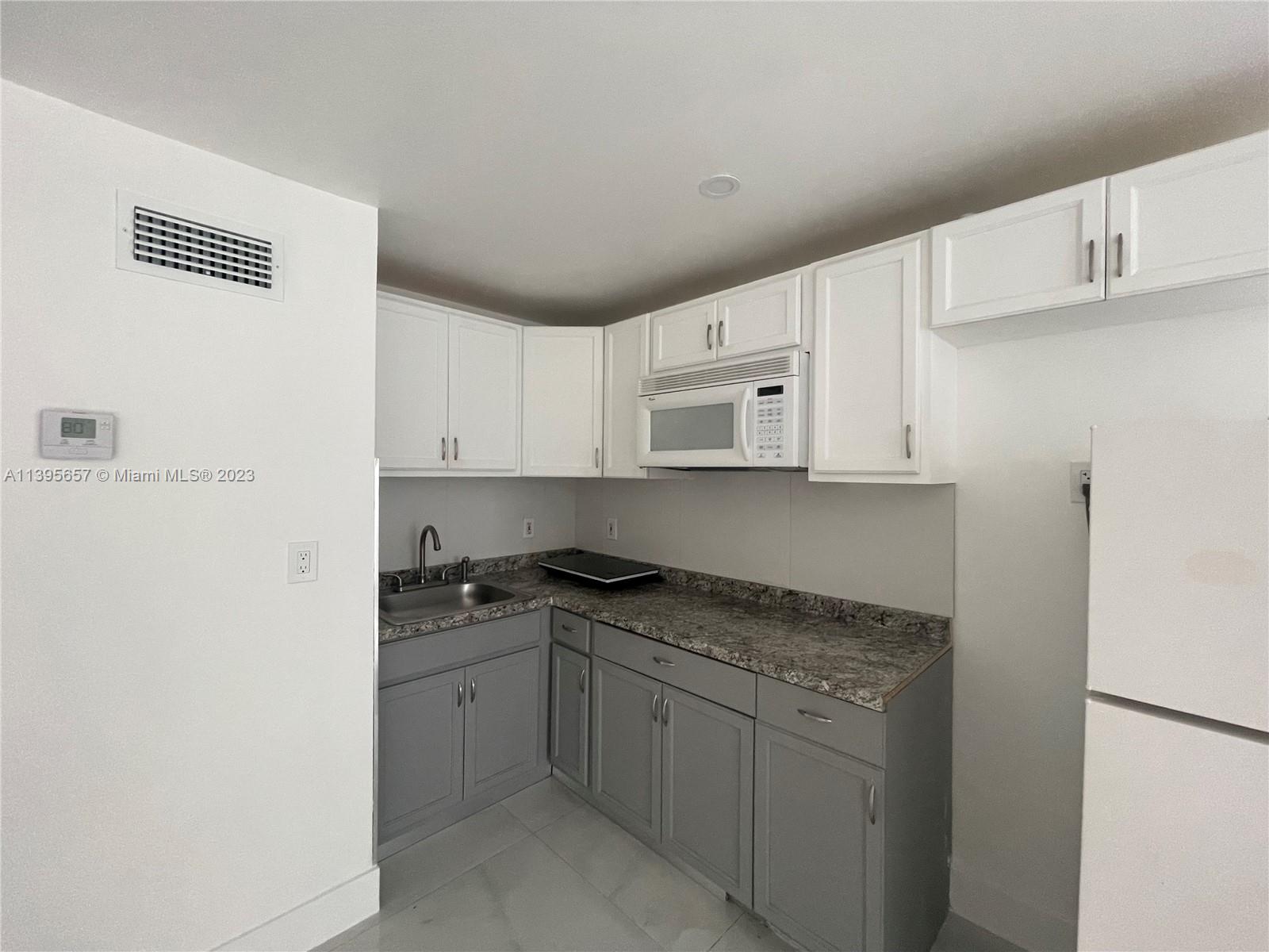 685 East 9th Lane Hialeah, FL 33010 - Photo 15 of 47 a kitchen with granite countertop white cabinets and white appliances
