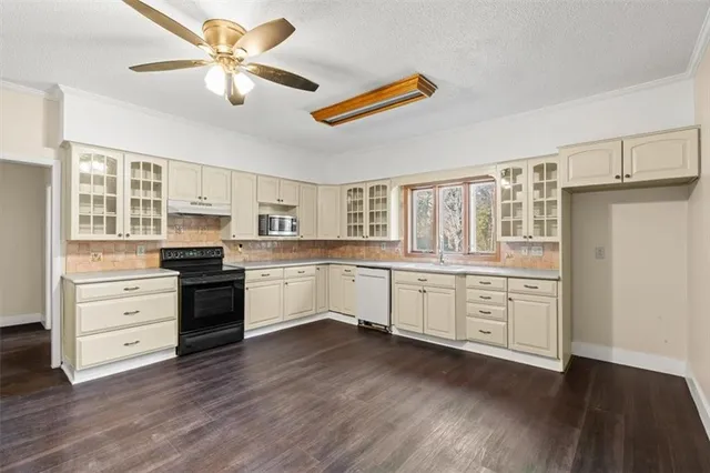 a kitchen with stainless steel appliances a stove and white cabinets with wooden floor