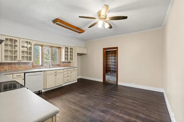 an empty room with wooden floor closet and windows
