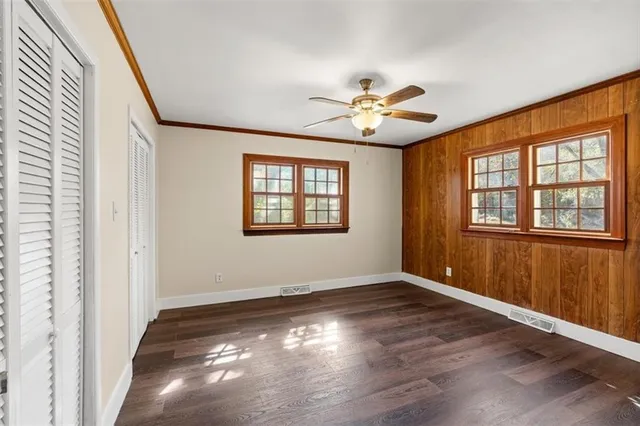 a view of empty room with wooden floor and fan