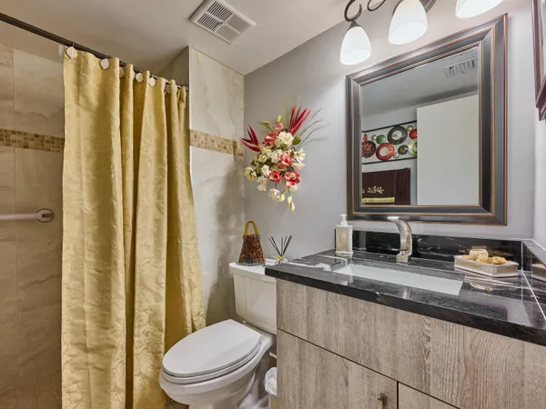 a bathroom with a granite countertop sink mirror vanity and toilet
