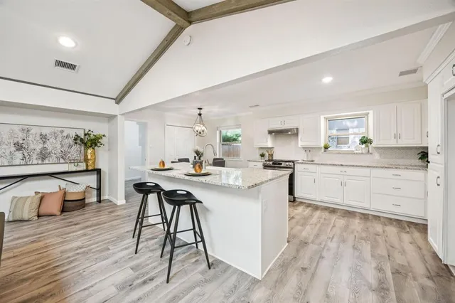 a kitchen with white cabinets appliances and furniture