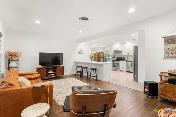 a living room with furniture and a flat screen tv with kitchen view