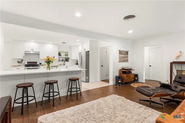 a living room with furniture a rug and kitchen view