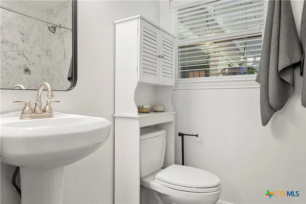 a bathroom with a sink a toilet and shower