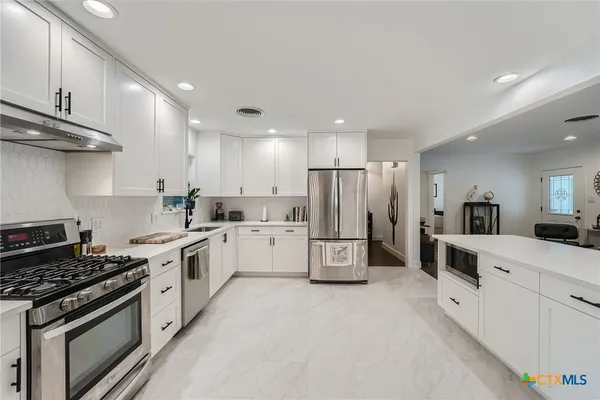 a kitchen with white cabinets and white appliances