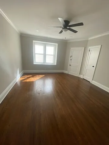 an empty room with wooden floor fan and windows