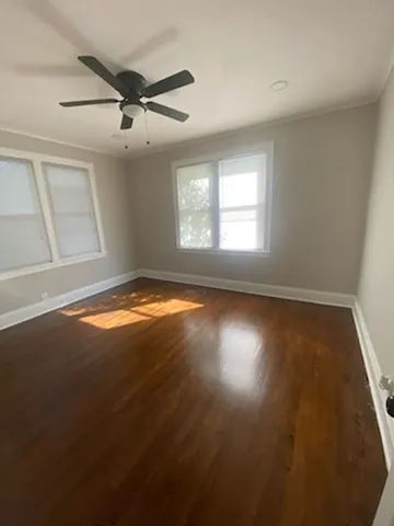 an empty room with wooden floor fan and windows
