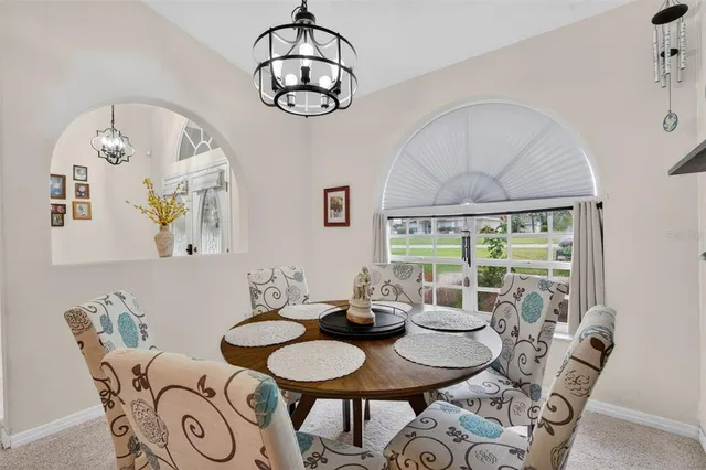 a living room with furniture kitchen view and a chandelier