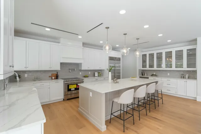 a large white kitchen with a large island oven a stove and a sink