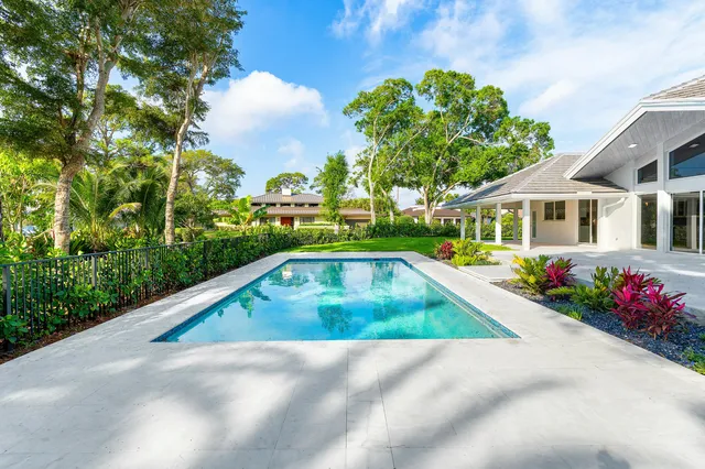 a aerial view of a house with swimming pool and trees in the background